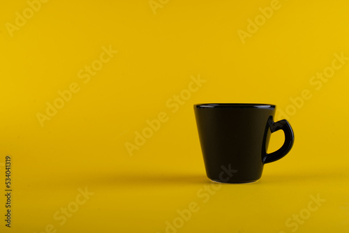 Black cup on yellow coffee. Cup insulated against the background