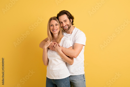 Happy handsome millennial caucasian guy hugging woman in white t-shirt, enjoy romance together