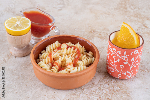 A clay bowl of delicious pasta with various vegetables photo