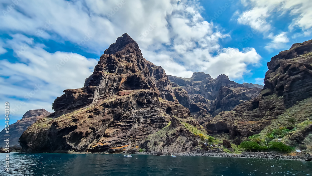 Panoramic view on the massive cliffs of Los Gigantes in Santiago del Teide, West coast Tenerife, Canary Islands, Spain, Europe. Rock formations along coastline of the Atlantic Ocean. Playa de Masca Panoramic view on the massive cliffs of Los Gigantes in Santiago del Teide, West coast Tenerife, Canary Islands, Spain, Europe. Rock formations along coastline of the Atlantic Ocean. Playa de Masca