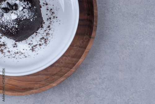 Delicious chocolate cake on a platter on a wooden tray on marble background
