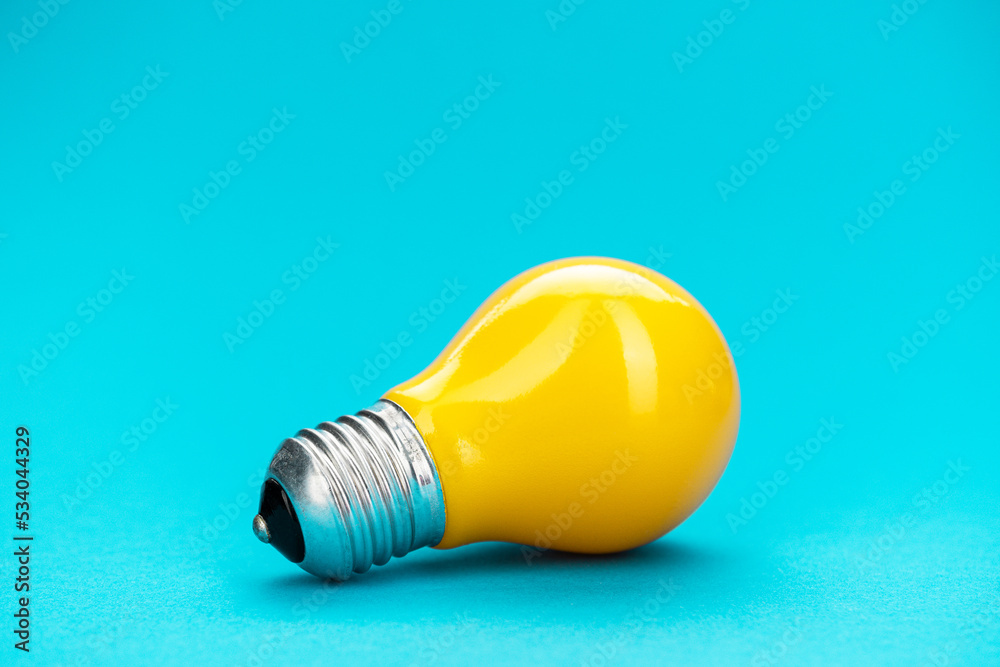 Yellow bulb on turquoise background with copy space. Minimalist photo of lightbulb over blue. Yellow bulb on turquoise background with copy space. Minimalist photo of lightbulb over blue.