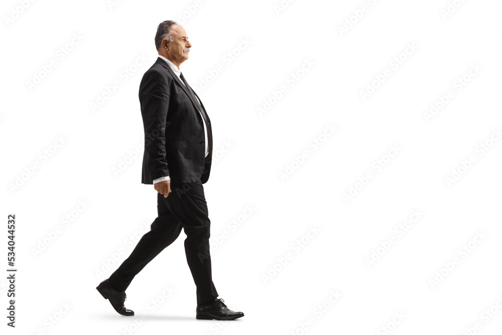 Full length profile shot of a mature businessman in a black suit walking Full length profile shot of a mature businessman in a black suit walking