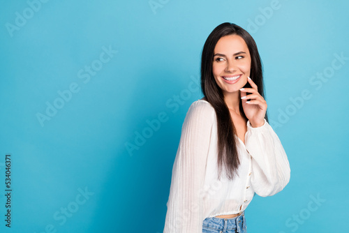 Photo of flirty dreamy girl dressed white blouse looking empty space finger cheek isolated blue color background photo