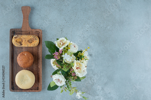 Small bundle of pastries on a small tray next to a vase of flowers on marble background