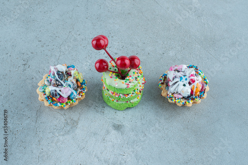 Candy cupcakes and small donuts on marble background