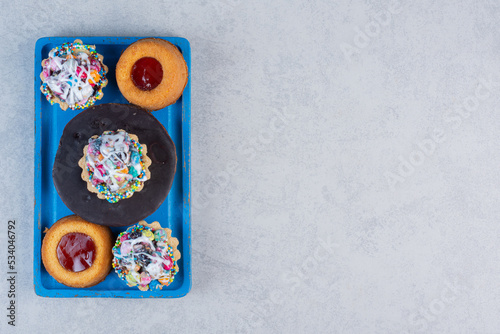 Small dessert assortment on a blue platter on marble background