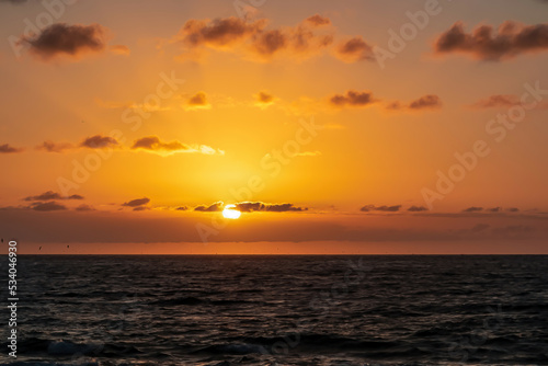 Scenic view during sunset from the beach Playa del Ingles in Valle Gran Rey, La Gomera, Canary Islands, Spain, Europe. Clouds emerging and turning orange red. Sun is going down behind the horizon © Chris