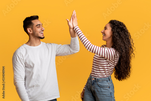 Foto Portrait Of Happy Young Arab Couple Giving High Five To Each Other
