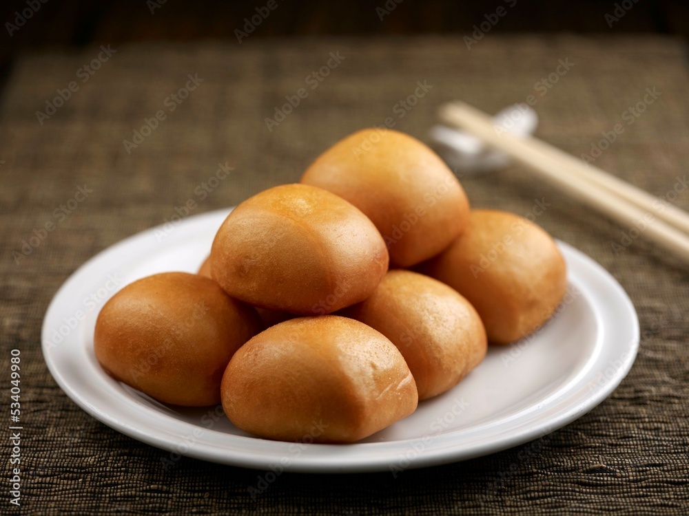Fried Mantou with chopsticks served in a dish isolated on table side view Fried Mantou with chopsticks served in a dish isolated on table side view