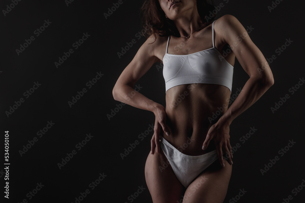 body shape of a sporty fitness girl studio photo on a dark background, the concept of sports and healthy eating