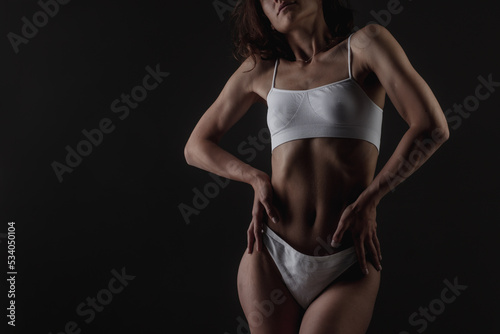 body shape of a sporty fitness girl studio photo on a dark background, the concept of sports and healthy eating