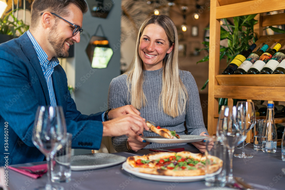 Romantic couple enjoying lunch in the restaurant, eating pizza and drinking wine. Lifestyle, love, relationships, food concept Romantic couple enjoying lunch in the restaurant, eating pizza and drinking wine. Lifestyle, love, relationships, food concept