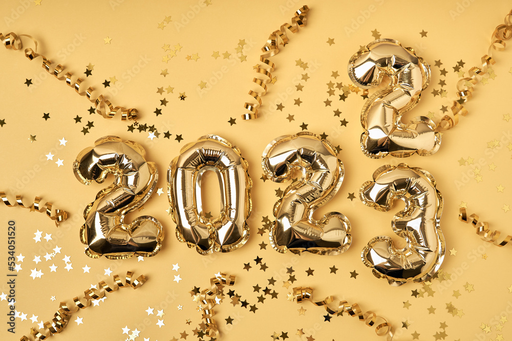 Φωτογραφία Foil gold air balloons in the form of numbers 2022 and 2023 on yellow background with confetti stars and party streamers