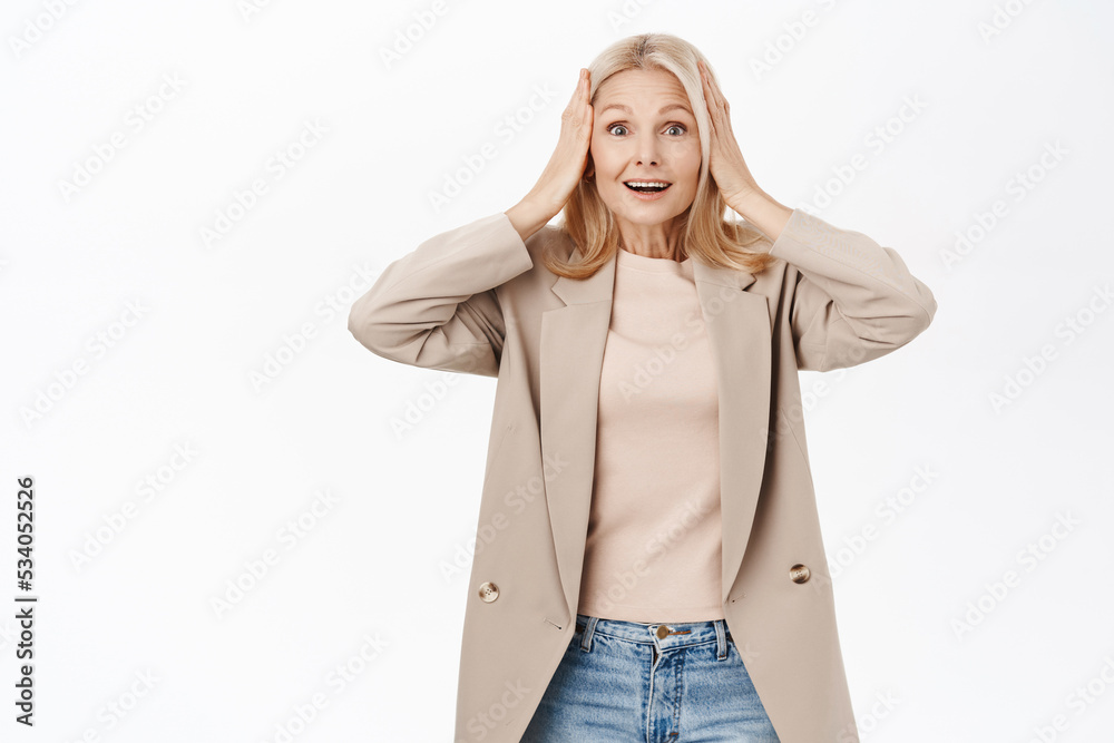 Portrait of beautiful mature woman, middle aged lady looks surprised, reacts amazed at news or announcement, stands over white background Portrait of beautiful mature woman, middle aged lady looks surprised, reacts amazed at news or announcement, stands over white background