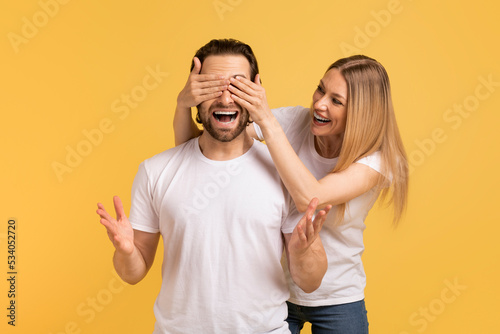 Smiling young caucasian woman in white t-shirt closes eyes to shocked man with open mouth