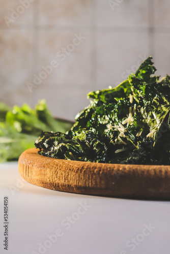 appetizing kale cabbage chips on a wooden plate cooked in a dehydrator close-up
