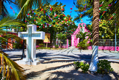 cross and church in the background with blue sky, palm trees and garden, isla aguada campeche  photo