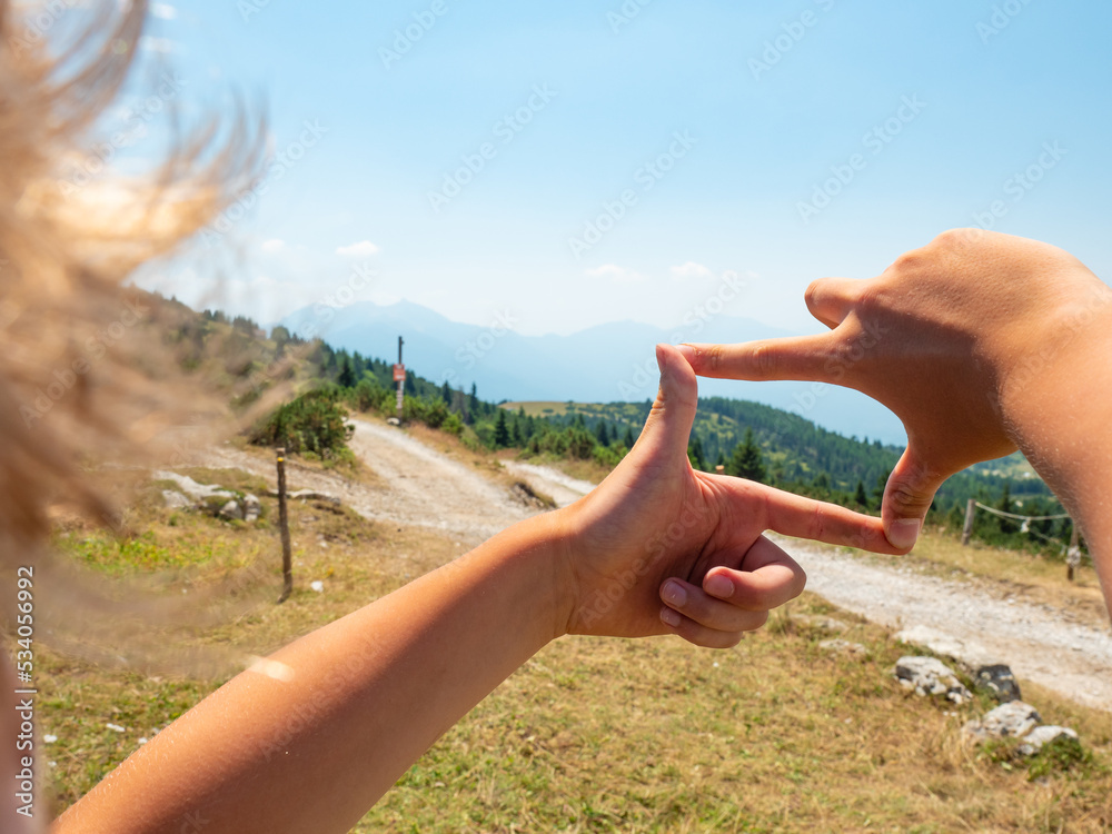 Φωτογραφία Boy is framing by fingers wooden tourist sign at gravel road to hill peak