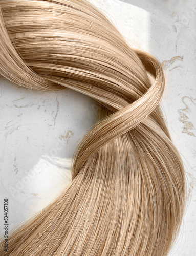 A strand of blond hair on a white background. Close-up.