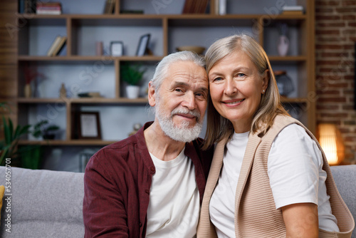 Mature happy couple smiling at the camera with a dazzling smile, beautiful teeth. Gray-haired husband and wife embrace each other. Relationships of happy seniors