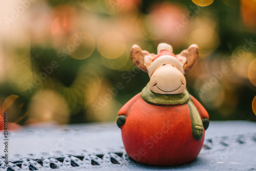 Cute Christmas moose in front of background with blurry Christmas lights. Christmas decorations. © Stefano Pessina