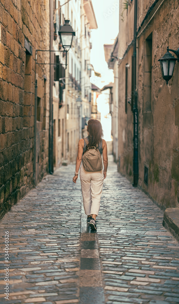 woman looking to the side as she walks down a street in Hondarribia
