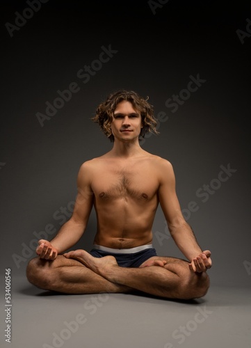 Shirtless young male meditating in Padmasana pose