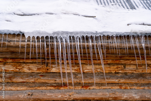 Icicles on roof of wooden private house resulting from improper construction of roof. Metal Downpipe system, Guttering System, External downpipes and drainage pipes at winter