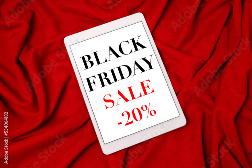 Black Friday sale shopping text on tablet screen on red fabric background.Sale promotion poster. Discount, sale season.