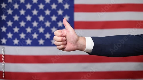 Thumbs up hand in approval with the United States flag in the background. Support for American politics and the American way of life. Vote for America photo
