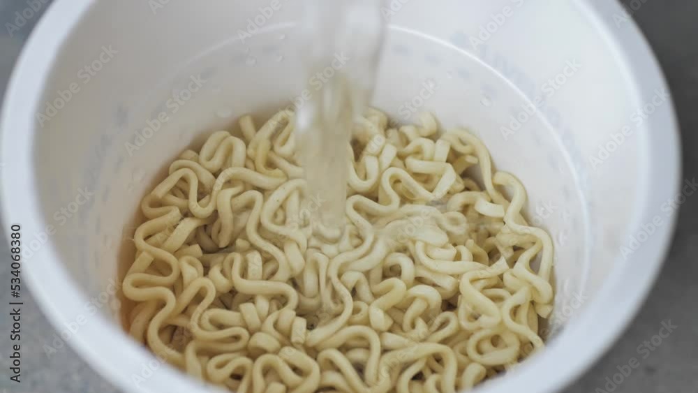 Pour boiling water from an electric kettle into cup noodles. Japanese