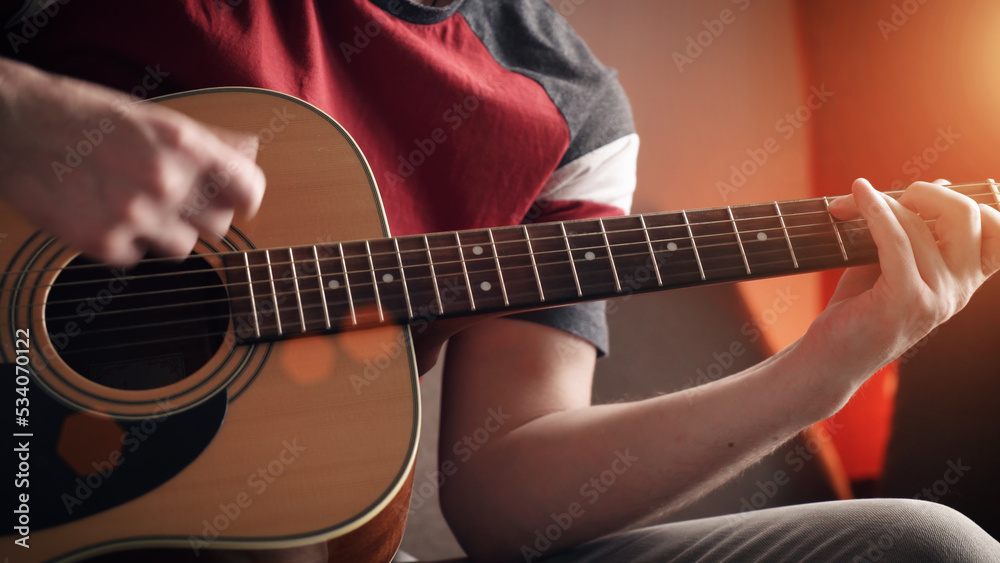 Fototapeta premium Young man learning to play acoustic guitar online at home. close-up.