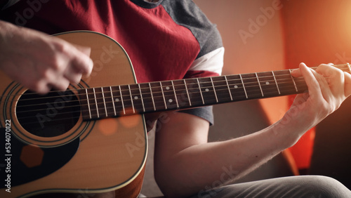 Young man learning to play acoustic guitar online at home. close-up.