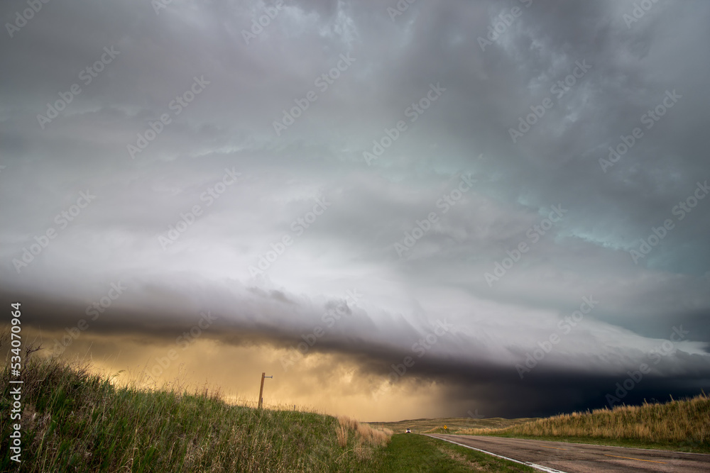 A shelf cloud and thunderstorm in the sky over a highway in the grasslands of Nebraska in the evening. A shelf cloud and thunderstorm in the sky over a highway in the grasslands of Nebraska in the evening.