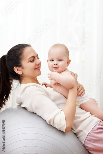 mother playing with her baby girl on a fitness ball