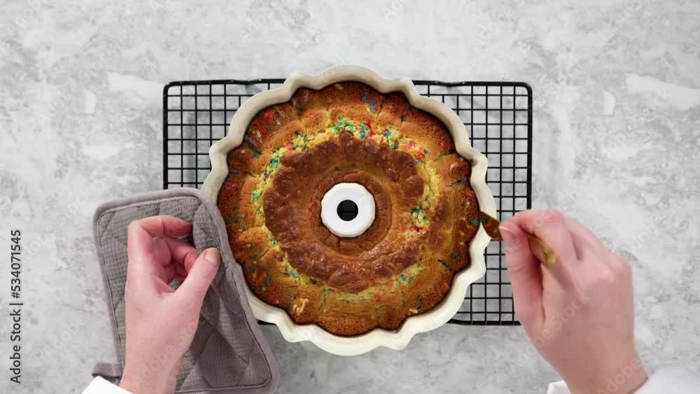 Flat lay. Removing freshly baked funfettti bundt cake from the bundt
