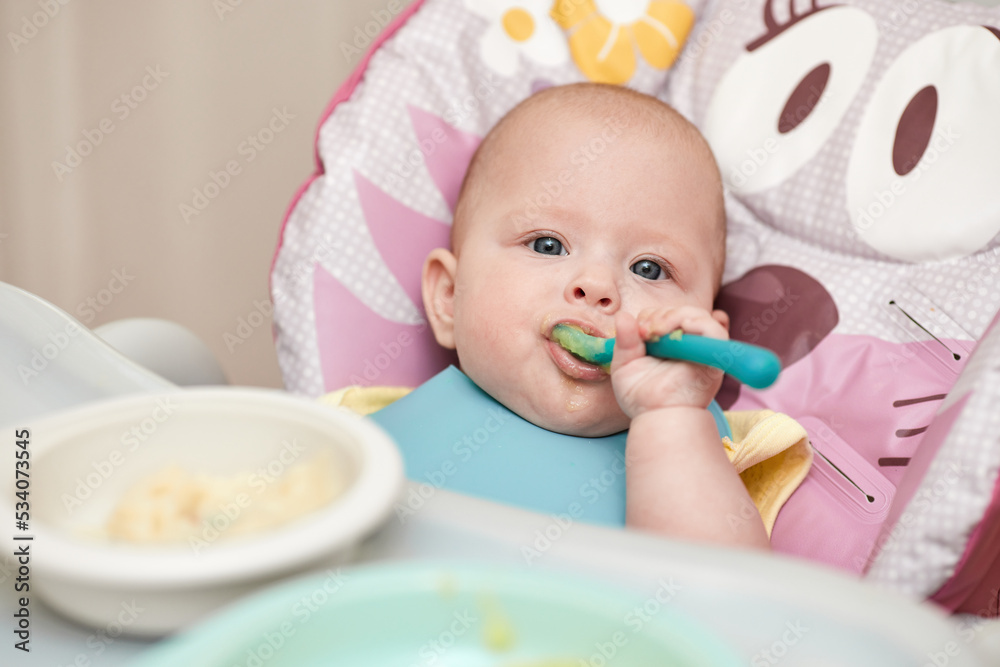cute baby girl eating with spoon in kitchen cute baby girl eating with spoon in kitchen