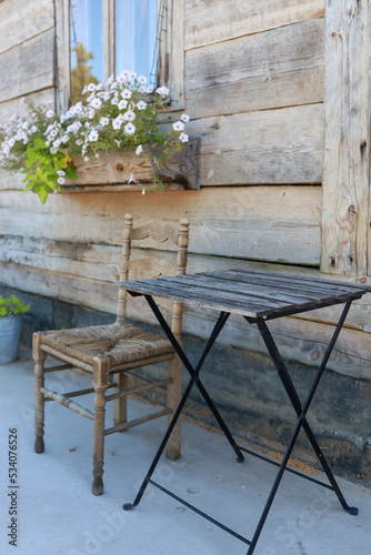 a beautiful wooden table and a wooden wicker chair near an old house or cafe in a rustic style
