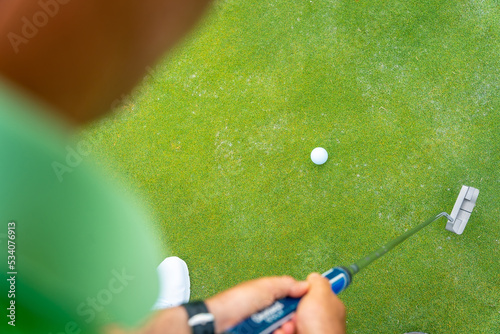 Man playing golf, detail of a shot with the putter on the green, view from above