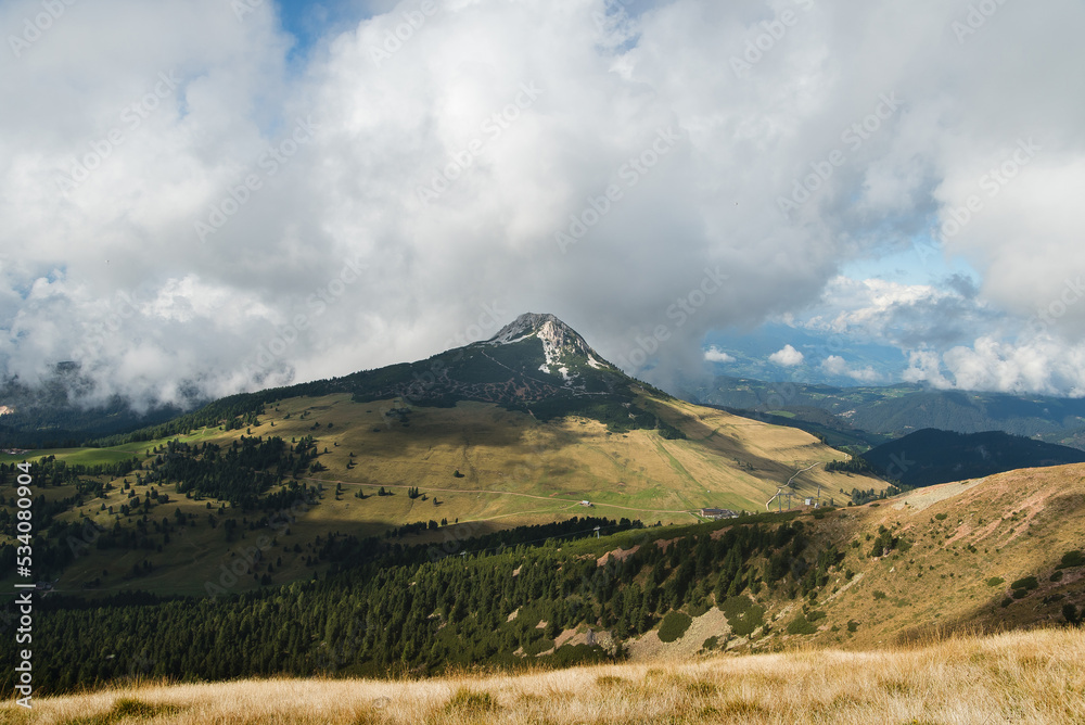 Naklejka premium Scenic beautiful alpine landscape with peak rocky mountains in dense low clouds in morning sunlight.