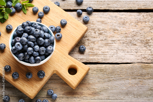 Tasty fresh blueberries on wooden table, flat lay. Space for text