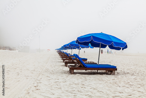 Obraz na plátně Blue Beach Loungers  A foggy day on the beach leaves these beach lounger chairs ready but vacant