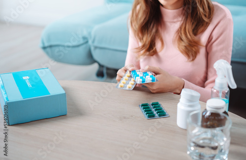 Asian young woman patient on eating table at nursing home care. Female look to medicine pills in bottle, read prescription and content. self recover health care concept.