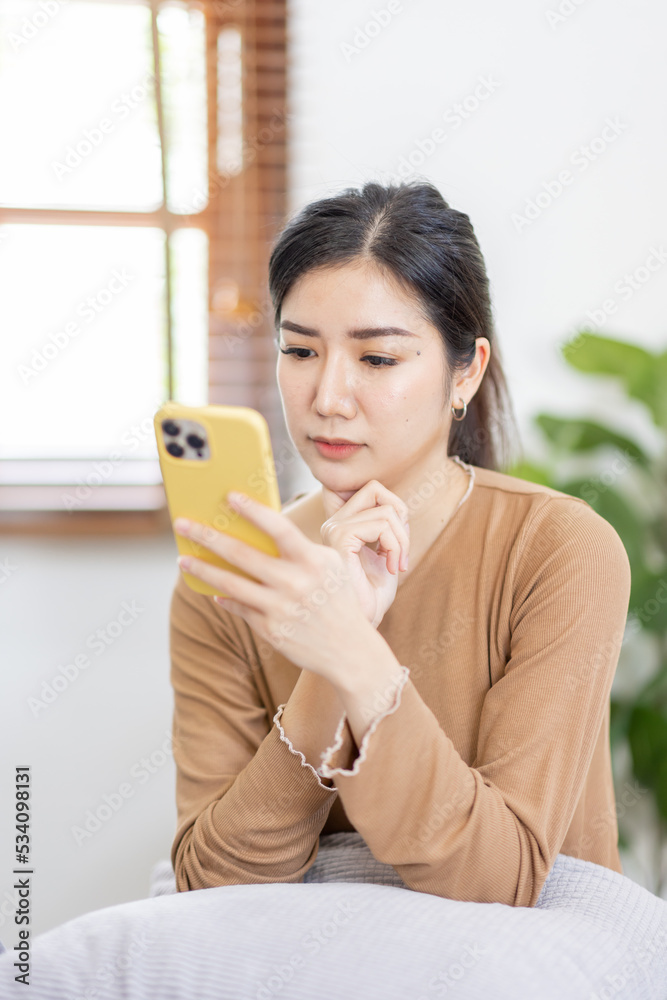 Beautiful Young Asian woman using smartphone on sofa at home, shopping online with internet in happy mood and Relax part time concept Beautiful Young Asian woman using smartphone on sofa at home, shopping online with internet in happy mood and Relax part time concept