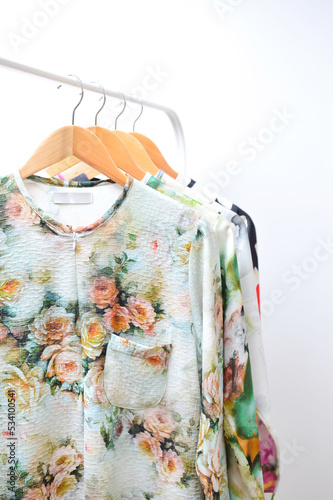 Close up collection of colorful woman blouse hanging on wooden clothes hanger in closet or clothing rack over white background, copy space. © doublealpha