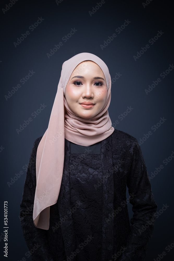 Portrait of a beautiful female model wearing hijab, a lifestyle apparel for Muslim women isolated on grey background. Idul Fitri and modern hijab fashion concept. Portrait of a beautiful female model wearing hijab, a lifestyle apparel for Muslim women isolated on grey background. Idul Fitri and modern hijab fashion concept.