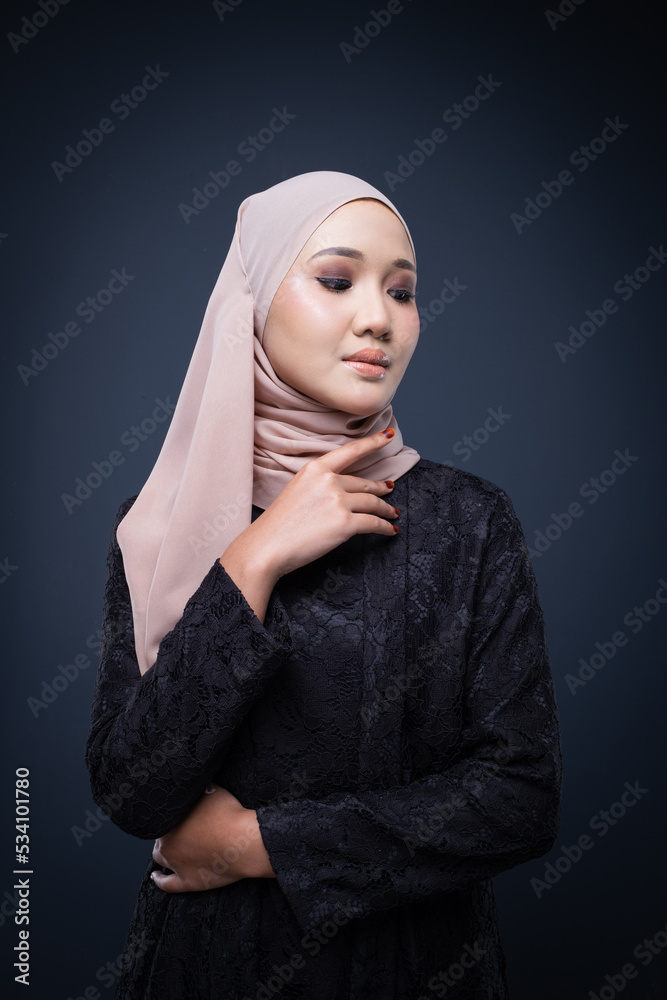 Portrait of a beautiful female model wearing hijab, a lifestyle apparel for Muslim women isolated on grey background. Idul Fitri and modern hijab fashion concept. Portrait of a beautiful female model wearing hijab, a lifestyle apparel for Muslim women isolated on grey background. Idul Fitri and modern hijab fashion concept.