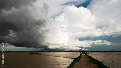 Low lying stormy weather front clouds rolling horizontally over the Tonle Sap lake with fish nets in foreground  and moving rain as the south east Asia monsoon season sets in.