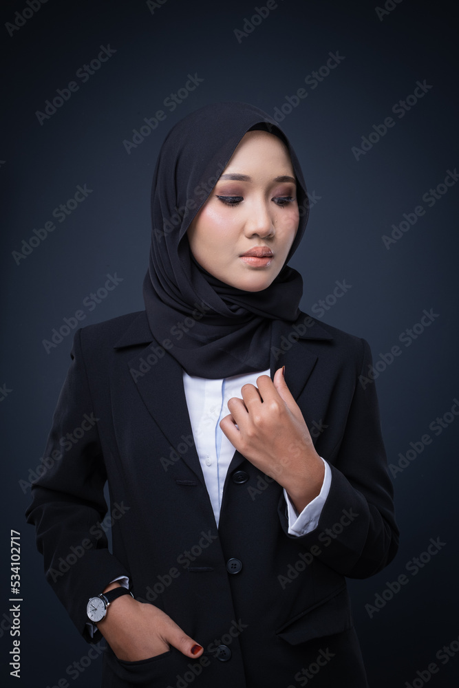 Portrait of an attractive Muslim woman wearing business attire and hijab with a corporate pose isolated on grey background. For image cut-out for technology, business or finance.
